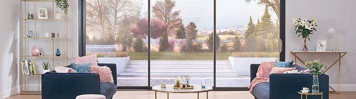 Stylish living room with two blue sofas, facing a large, black Origin OS-44 sliding door with a garden view