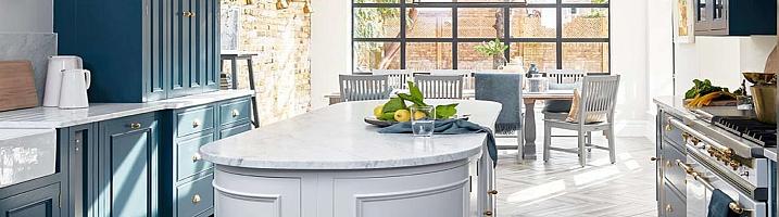 Modern kitchen with blue cabinets and a grey island, with a large, black Aluco steel-look window in the dining area behind