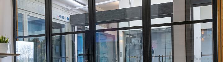 A large, black steel-replacement internal screen and door set with a grid pattern, installed in a modern showroom.