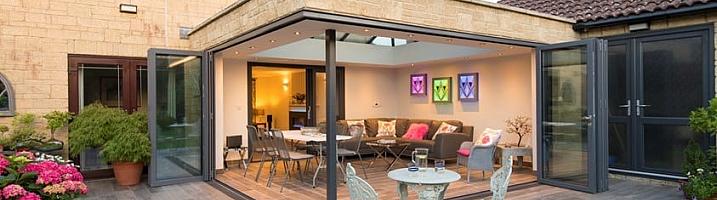 Patio extension with grey Origin bifold doors open to a lit living space, with a second set of doors on the right