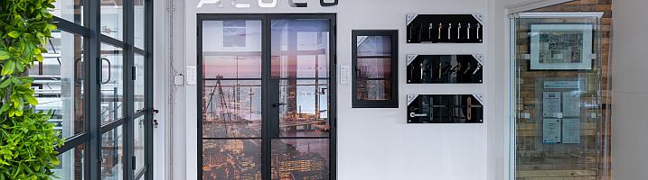 Wide view of the Aluco showroom display wall, featuring steel-look doors, a window, handle options, and a green wall