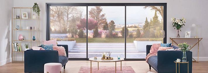 Stylish living room with two blue sofas, facing a large, black Origin OS-44 sliding door with a garden view