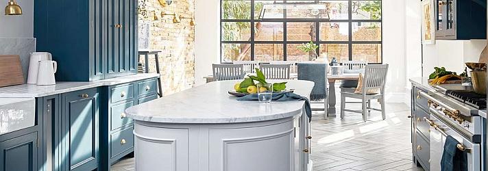Modern kitchen with blue cabinets and a grey island, with a large, black Aluco steel-look window in the dining area behind