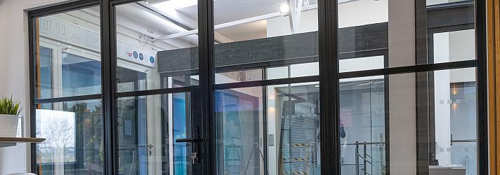 A large, black steel-replacement internal screen and door set with a grid pattern, installed in a modern showroom.