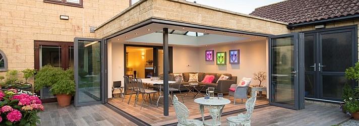 Patio extension with grey Origin bifold doors open to a lit living space, with a second set of doors on the right