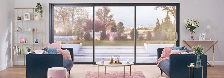 Stylish living room with two blue sofas, facing a large, black Origin OS-44 sliding door with a garden view