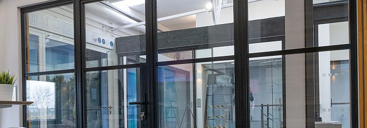 A large, black steel-replacement internal screen and door set with a grid pattern, installed in a modern showroom.