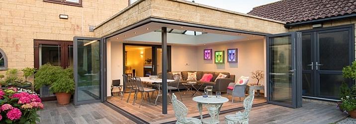 Patio extension with grey Origin bifold doors open to a lit living space, with a second set of doors on the right