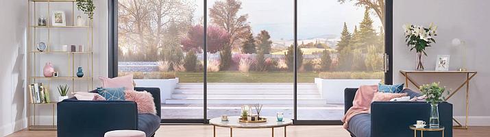 Stylish living room with two blue sofas, facing a large, black Origin OS-44 sliding door with a garden view