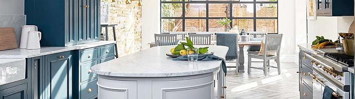 Modern kitchen with blue cabinets and a grey island, with a large, black Aluco steel-look window in the dining area behind
