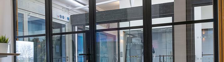 A large, black steel-replacement internal screen and door set with a grid pattern, installed in a modern showroom.