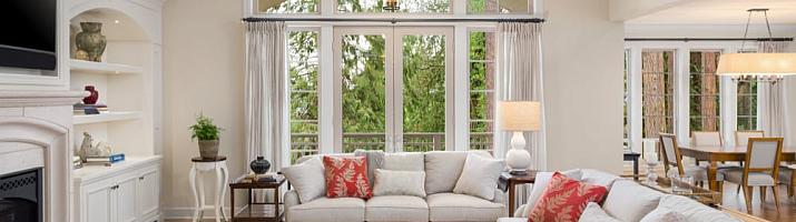 Elegant living room with white aluminium French doors and a large arched window on top, looking out to a garden