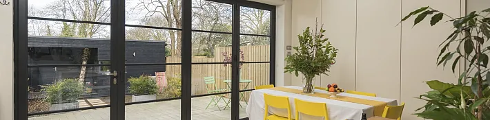 Black Origin OB-49 bifold doors with a steel-look grid, viewed from a modern kitchen, looking onto a patio