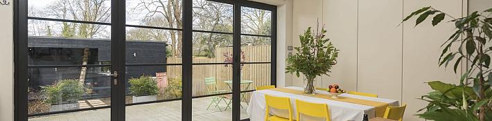 Black Origin OB-49 bifold doors with a steel-look grid, viewed from a modern kitchen, looking onto a patio