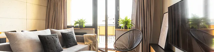 Living room with herringbone floors and a set of open double doors leading out onto a sunny balcony