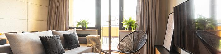 Living room with herringbone floors and a set of open double doors leading out onto a sunny balcony