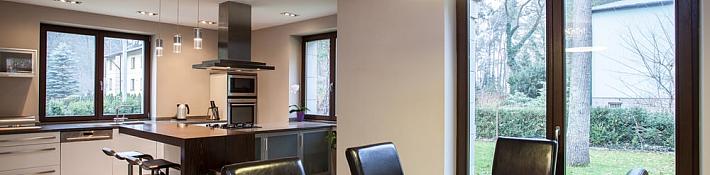 Open-plan kitchen and dining room with a dark-framed double door leading from the dining table out to the garden