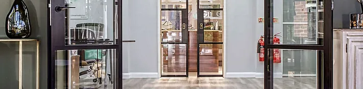 A bright showroom hallway with multiple black steel-look internal doors and screens installed