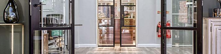 A bright showroom hallway with multiple black steel-look internal doors and screens installed