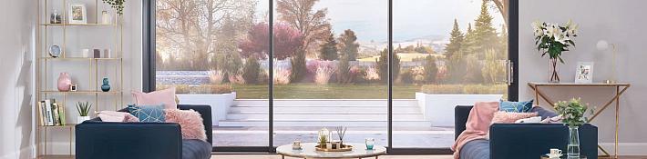 Stylish living room with two armchairs, looking out through a large, black-framed sliding door onto a patio