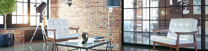 An industrial-style room with brick walls, featuring a large black steel-replacement window and a matching internal screen