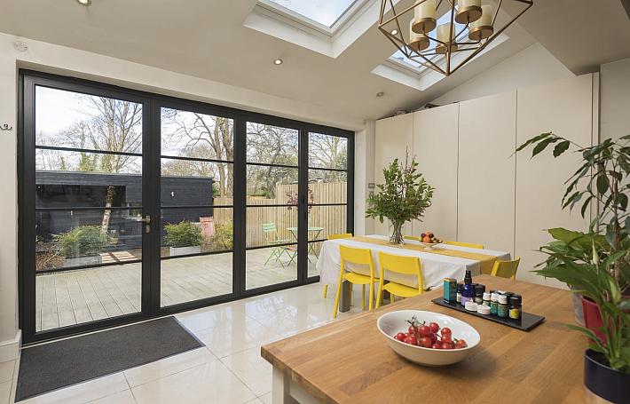 Black Origin OB-49 bifold doors with a steel-look grid, viewed from a modern kitchen, looking onto a patio