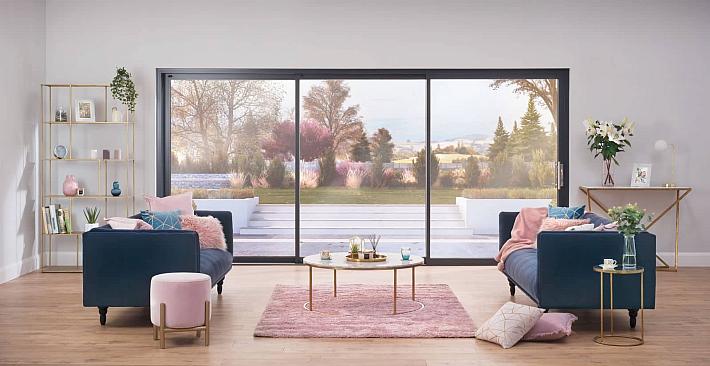Stylish living room with two blue sofas, facing a large, black Origin OS-44 sliding door with a garden view