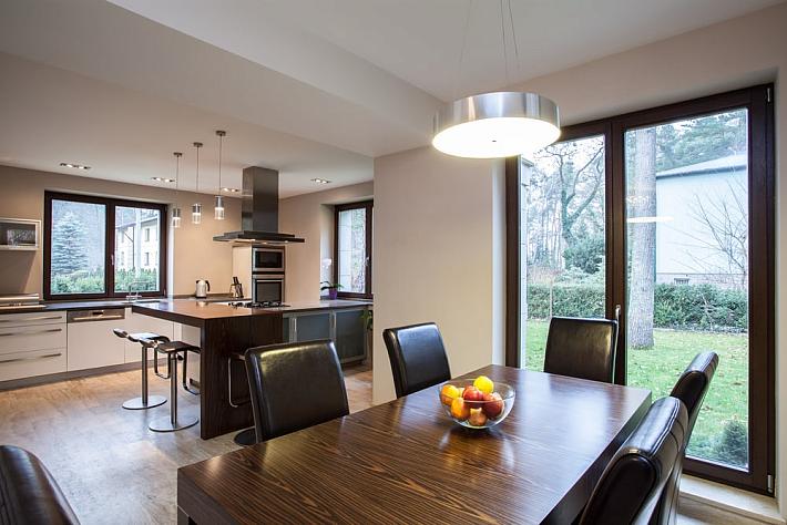 Open-plan kitchen and dining room with a dark-framed double door leading from the dining table out to the garden