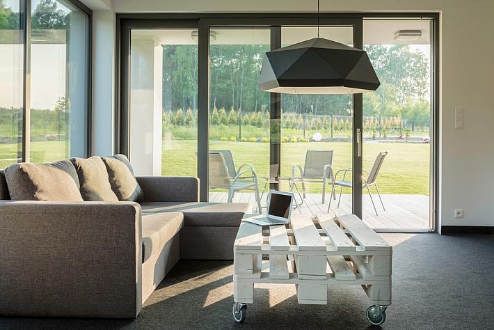 Modern living room with a grey sofa and a large Dutemann lift and slide door looking out onto a garden deck