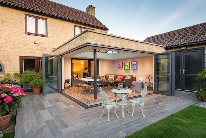 Patio extension with grey Origin bifold doors open to a lit living space, with a second set of doors on the right