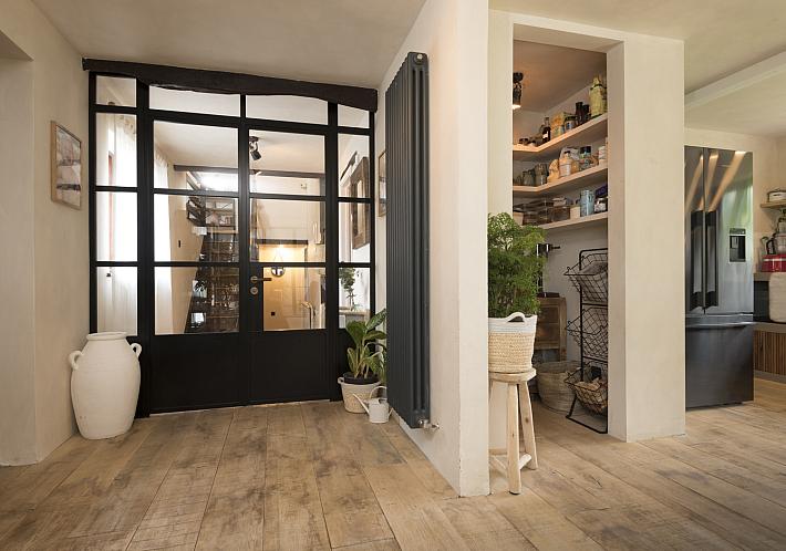 Rustic hallway with a large black steel-look internal door, featuring a grid pattern and solid bottom panel