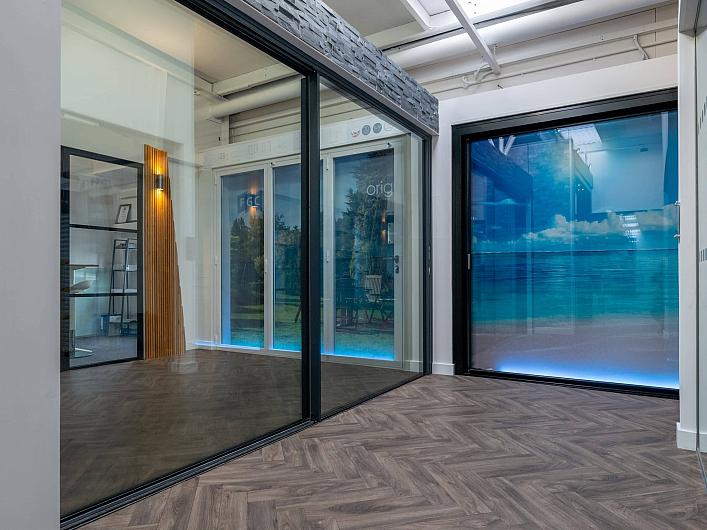 A modern showroom with herringbone floors, displaying large black and white Origin sliding door products