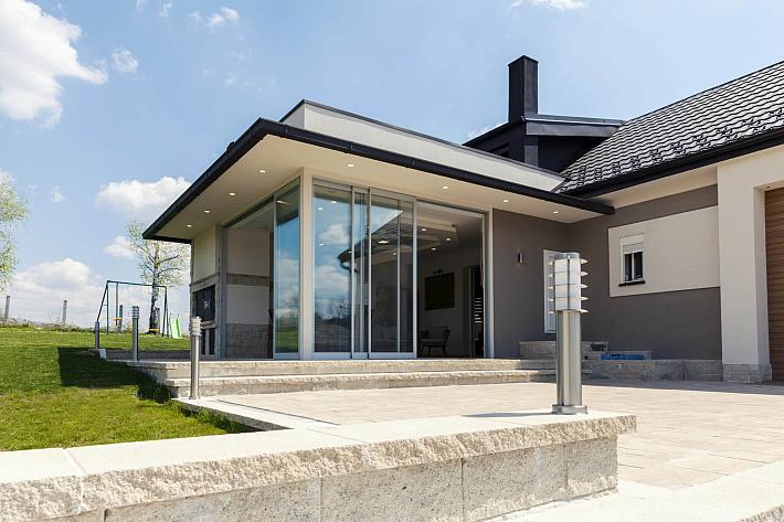 Exterior of a modern house with a large patio and a set of white-framed sliding doors, viewed from the garden