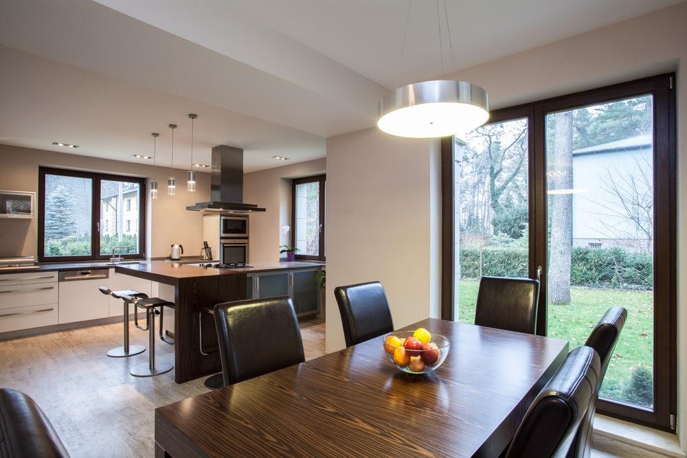 Open-plan kitchen and dining room with a dark-framed double door leading from the dining table out to the garden