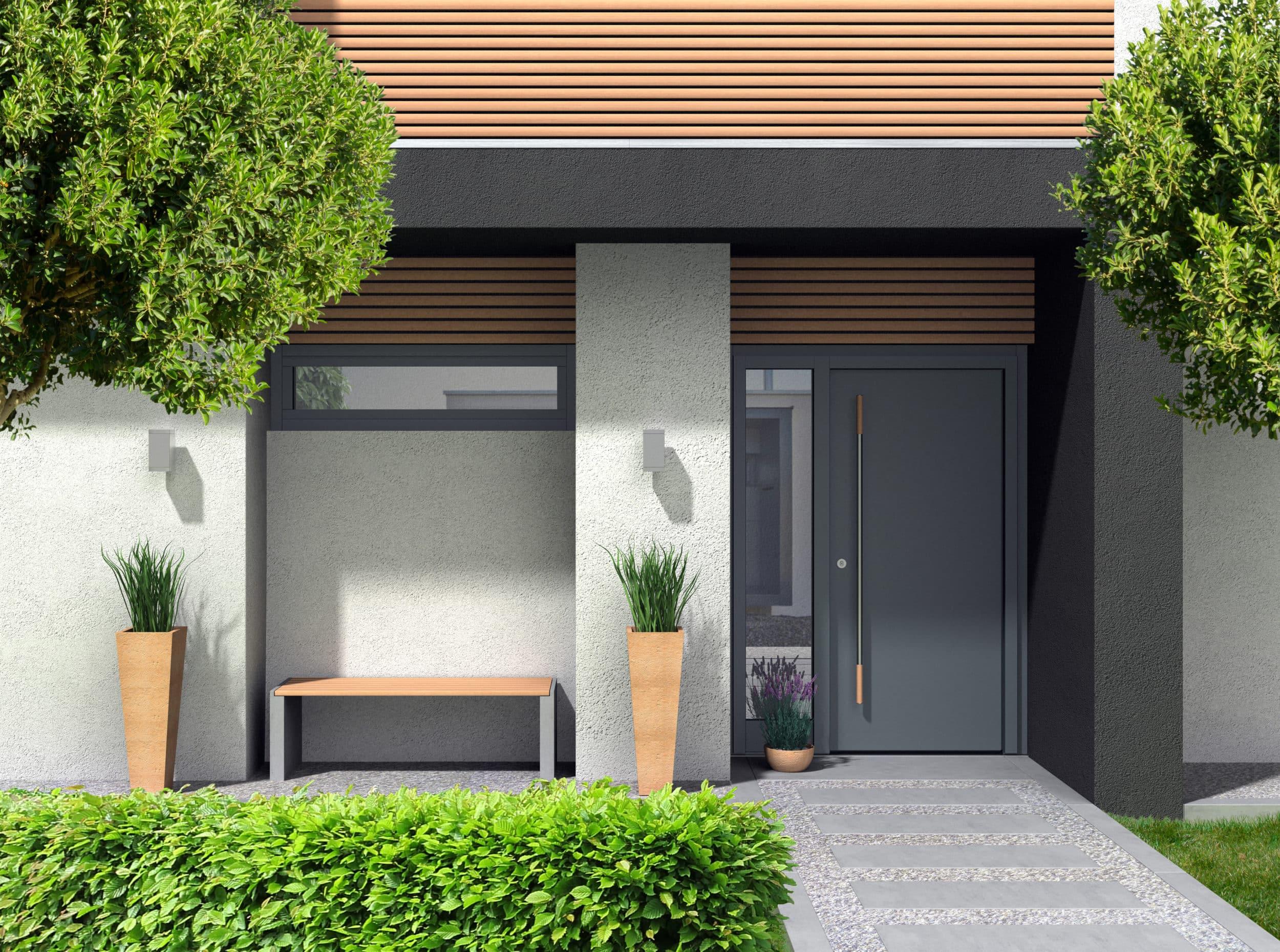 A modern, solid dark grey entrance door with a long vertical handle, set into a contemporary house exterior with wood slat details