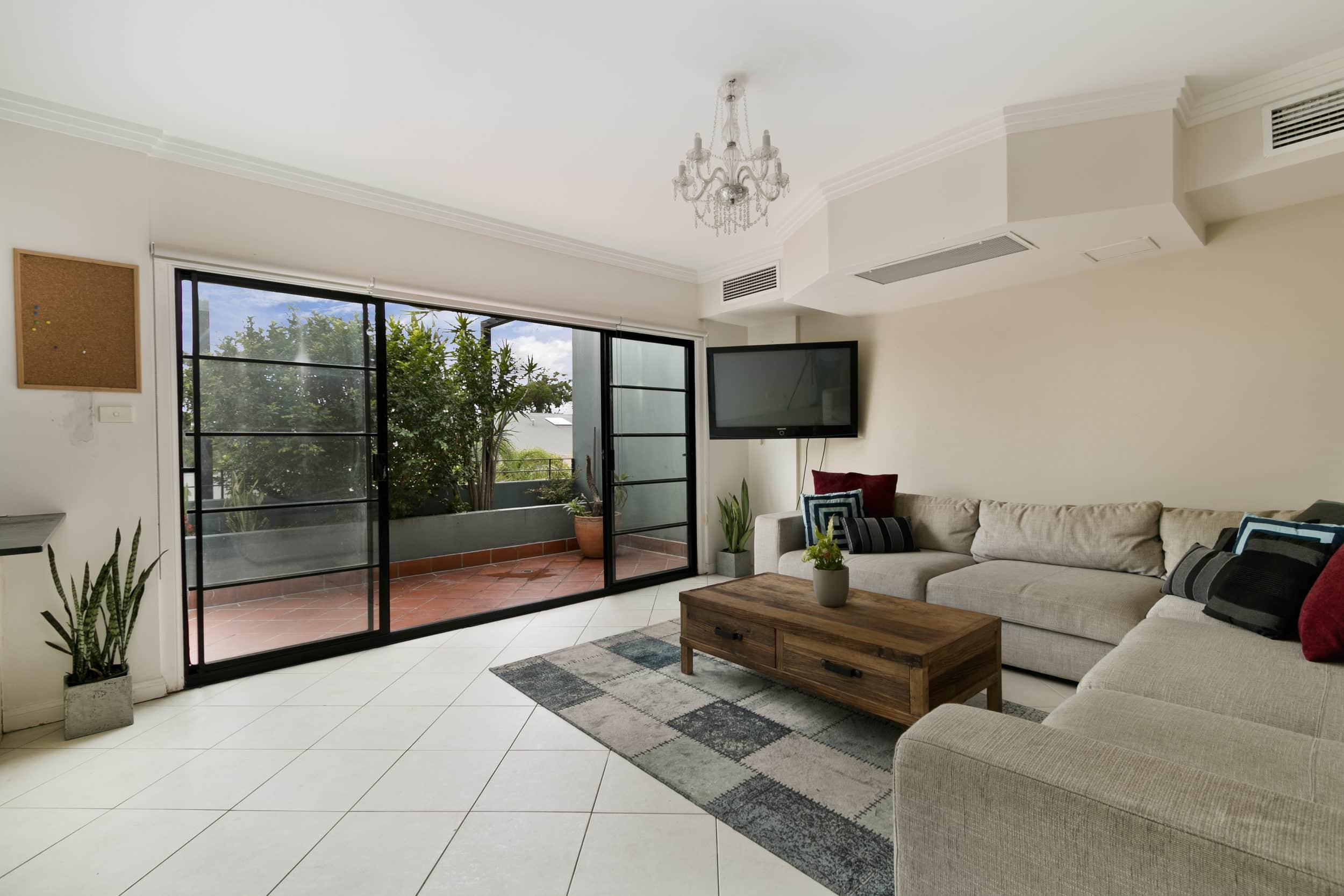 A living room with a sofa and a black steel-replacement sliding door with horizontal bars, leading to a balcon