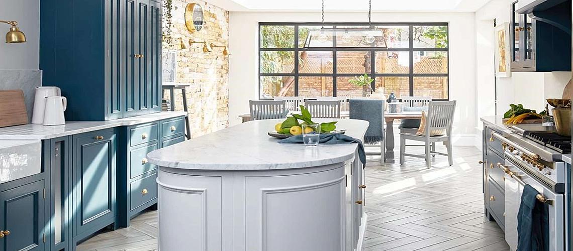Modern kitchen with blue cabinets and a grey island, with a large, black Aluco steel-look window in the dining area behind