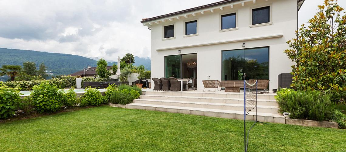 White modern house with a lawn and patio, featuring large Origin sliding glass doors