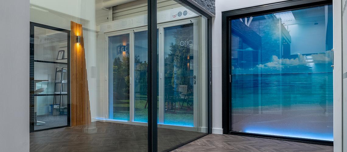 Modern showroom with herringbone floors, displaying large black sliding doors and a white Origin bifold door