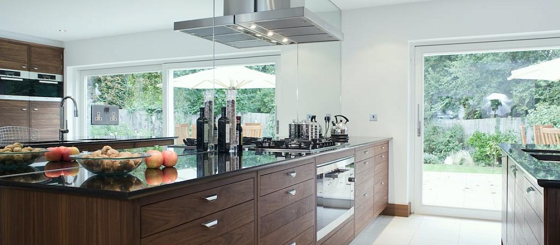 Modern kitchen with wood cabinets and a large Origin sliding door and a single Origin door leading to the garden
