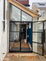 Exterior view of a black heritage door and apex window on an unfinished extension. One of the double doors is open