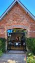 Exterior view of a red brick building with arched black steel-look doors fully open, looking from the patio into the kitchen