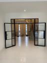 Open black steel-look double doors looking out from a room into a main entrance hall with a staircase and front door