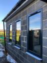 Exterior view of the three tall, dark grey windows set in the concrete block wall of the new extension