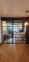 Straight-on view of closed black steel-look double doors with grid panes, installed under a dark wooden beam