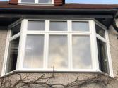 Exterior view of a white multi-section Origin bay window, fully closed, on a pebble-dash house