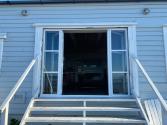 White steel-look bifold doors on a blue clad building, shown fully open and viewed from the bottom of the stairs