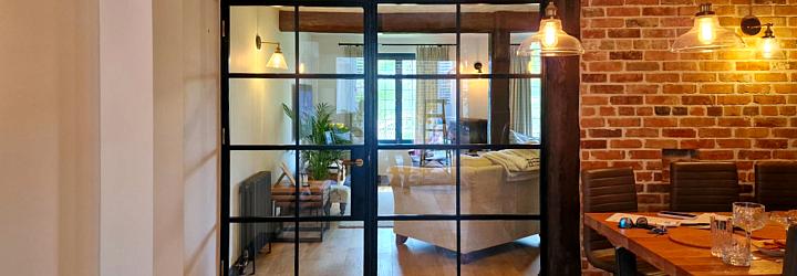 Closed black steel-look double doors with grid pattern, separating a dining area from a living room with a sofa