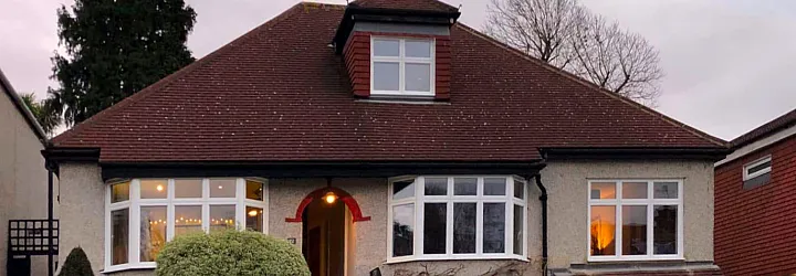 Close-up of a white Origin bay window on a pebble-dash house. The right-hand casement window is fully open
