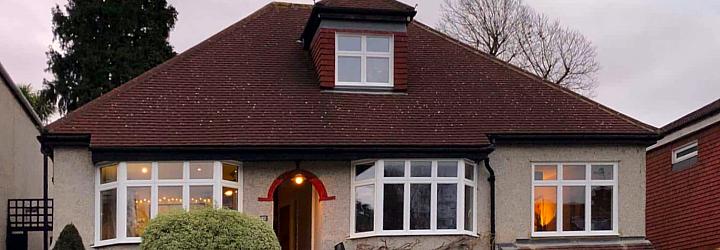 Close-up of a white Origin bay window on a pebble-dash house. The right-hand casement window is fully open